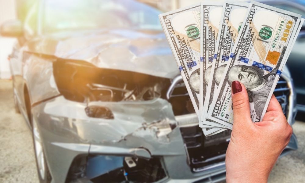 A woman holding money in front of a salvage vehicle