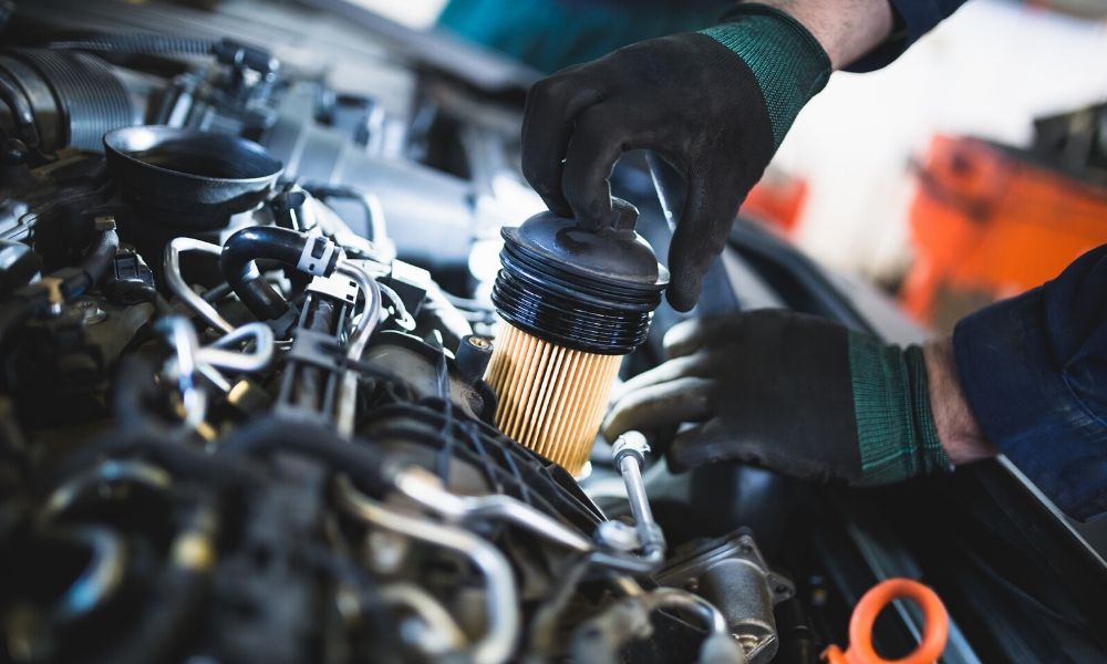 A technician replacing the fuel filter in a modern sedan-style car.