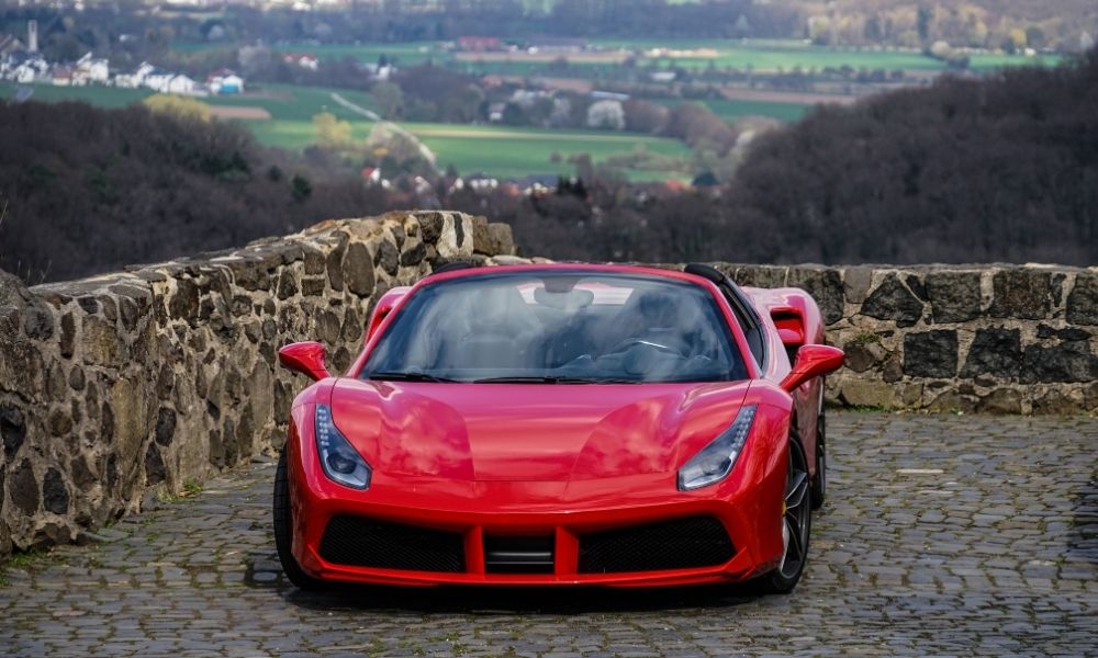 A red sports car parked in scenic mountain area.